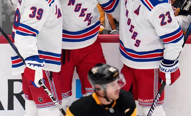 New York Rangers' Mika Zibanejad (93) celebrates his goal with Sam Carrick (39) and Adam Fox (23) as Pittsburgh Penguins' Sidney Crosby (87) skates back to the bench during the first period of an NHL hockey game in Pittsburgh, Saturday, Oct. 11, 2025. (AP Photo/Gene J. Puskar)