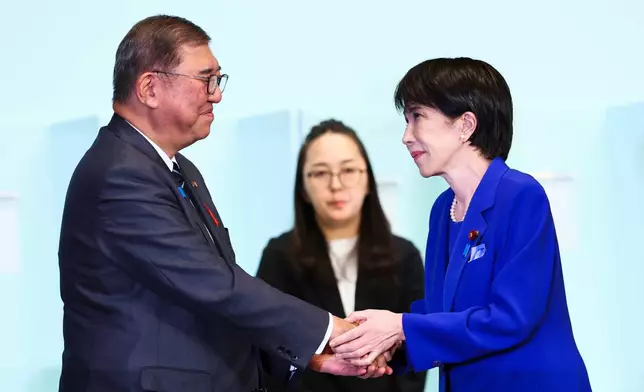 Newly-elected leader of Japan's Liberal Democratic Party (LDP) Sanae Takaichi, right, shakes hands with Prime Minister Shigeru Ishiba after winning the LDP leadership election i in Tokyo, Japan, Saturday, Oct. 4, 2025. (Kim Kyung-Hoon/Pool Photo via AP)