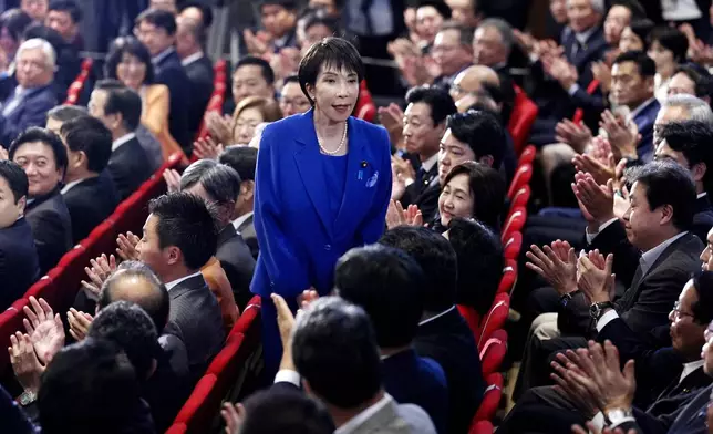 Former Economic Security Minister Sanae Takaichi, center, stands as Takaichi was chosen to a new leader of Japan’s ruling Liberal Democratic Party during the party's leadership election in Tokyo, Japan, Saturday, Oct. 4, 2025. (Kyodo News via AP)