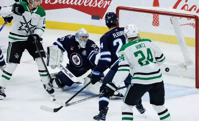 Dallas Stars' Jason Robertson (21) and Roope Hintz (24) look on as a shot by Nils Lundkvist (not shown) gets past Winnipeg Jets goaltender Connor Hellebuyck (37) during first-period NHL hockey game action in Winnipeg, Manitoba, Thursday, Oct. 9, 2025. (John Woods/The Canadian Press via AP)