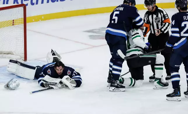 Winnipeg Jets' Luke Schenn (5) roughs up Dallas Stars' Roope Hintz (24) after Hintz fell on Jets' goaltender Connor Hellebuyck (37) during second-period NHL hockey game action in Winnipeg, Manitoba, Thursday, Oct. 9, 2025. (John Woods/The Canadian Press via AP)