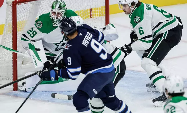 Dallas Stars goaltender Jake Oettinger (29) saves a shot as Winnipeg Jets' Alex Iafallo (9) looks on during first-period NHL hockey game action in Winnipeg, Manitoba, Thursday, Oct. 9, 2025. (John Woods/The Canadian Press via AP)