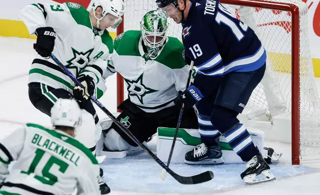 Dallas Stars' Esa Lindell (23) and goaltender Jake Oettinger, center top, defend against Winnipeg Jets' Jonathan Toews (19) during second-period NHL hockey game action in Winnipeg, Manitoba, Thursday, Oct. 9, 2025. (John Woods/The Canadian Press via AP)