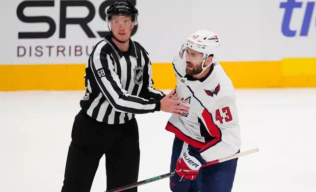 Washington Capitals' Tom Wilson (43) is escorted to the penalty box by linesman CJ Murray (68) in the first period of an NHL hockey game against the Dallas Stars Tuesday, Oct. 28, 2025, in Dallas. (AP Photo/Tony Gutierrez)
