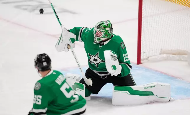 Dallas Stars goaltender Jake Oettinger (29) blocks a shot as Thomas Harley (55) looks on in the first period of an NHL hockey game against the Washington Capitals Tuesday, Oct. 28, 2025, in Dallas. (AP Photo/Tony Gutierrez)
