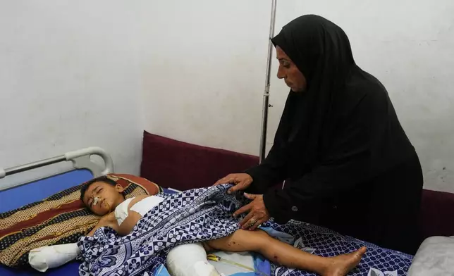 Hanan Shakshk cares her grandson Yahya Shorbasi, who was injured by an unexploded ordnance along with his six-year-old twin sister Nabila, at Shifa Hospital in Gaza City, Saturday, Oct. 25, 2025. (AP Photo/Abdel Kareem Hana)
