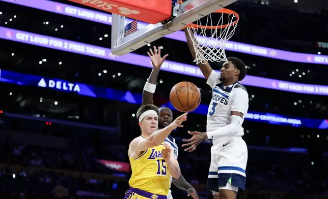 Los Angeles Lakers guard Austin Reaves (15) passes the ball against Minnesota Timberwolves forwards Julius Randle, back left, and Jaden McDaniels (3) during the first half of an NBA basketball game, Friday, Oct. 24, 2025, in Los Angeles. (AP Photo/Jessie Alcheh)