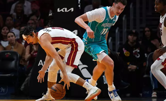 Miami Heat guard Jaime Jaquez Jr. (11) picks up the ball in front of Charlotte Hornets center Ryan Kalkbrenner (11) during the first half of an NBA basketball game, Tuesday, Oct. 28, 2025, in Miami. (AP Photo/Michael Laughlin)