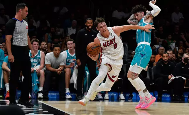 Miami Heat guard Pelle Larsson (9) dribbles past Charlotte Hornets guard Lamelo Ball during the first half of an NBA basketball game, Tuesday, Oct. 28, 2025, in Miami. (AP Photo/Michael Laughlin)
