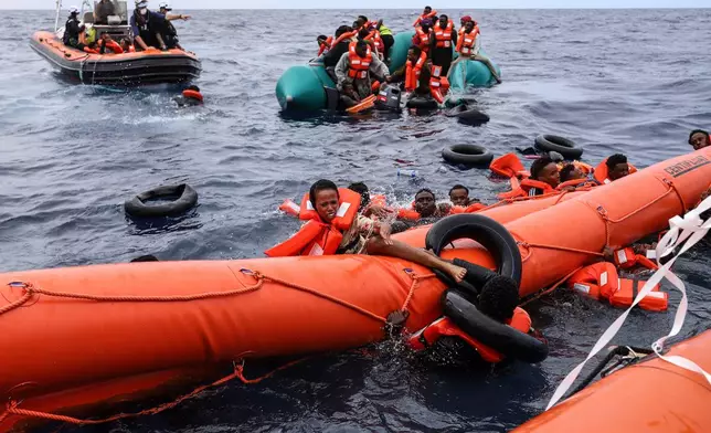 FILE - Migrants who fell in the water struggle to cling on to a a float before being rescued by a humanitarian rescuers, around 35 miles away from Libya, in the Mediterranean Sea, Oct. 18, 2021. (AP Photo/Valeria Mongelli, File) (AP Photo/Valeria Mongelli, File)
