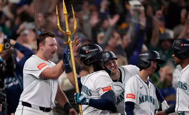 Seattle Mariners' Eugenio Suárez holds the trident after hitting a grand slam home run during the eighth inning in Game 5 of baseball's American League Championship Series against the Toronto Blue Jays, Friday, Oct. 17, 2025, in Seattle. (AP Photo/Lindsey Wasson)