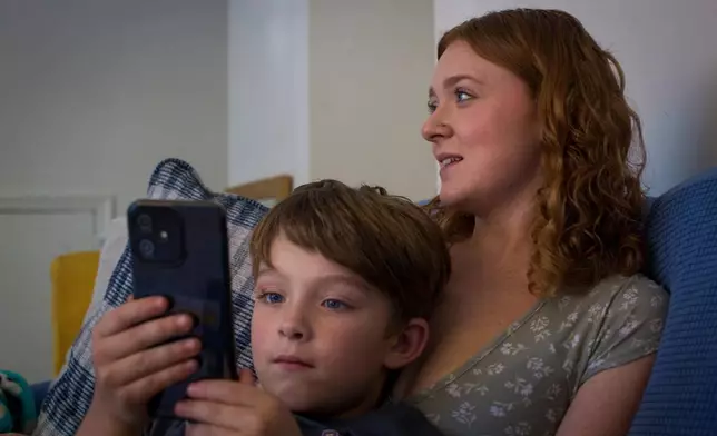 Taylor Moyer watches TV with her oldest son Liam at home, Sunday, Oct. 5, 2025, in Virginia Beach, Va. (AP Photo/John Clark)