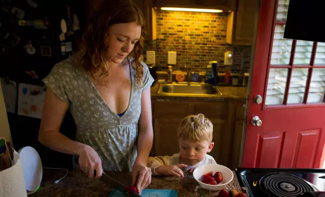 Taylor Moyer slices strawberries as her youngest son, Bradley, helps put the sliced fruit into a bowl while at home in the kitchen, Sunday, Oct. 5, 2025, in Virginia Beach, Va. (AP Photo/John Clark)