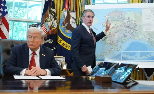 President Donald Trump listens as Interior Secretary Doug Burgum speaks to reporters in the Oval Office at the White House, Monday, Oct. 6, 2025, in Washington. (AP Photo/Jacquelyn Martin)