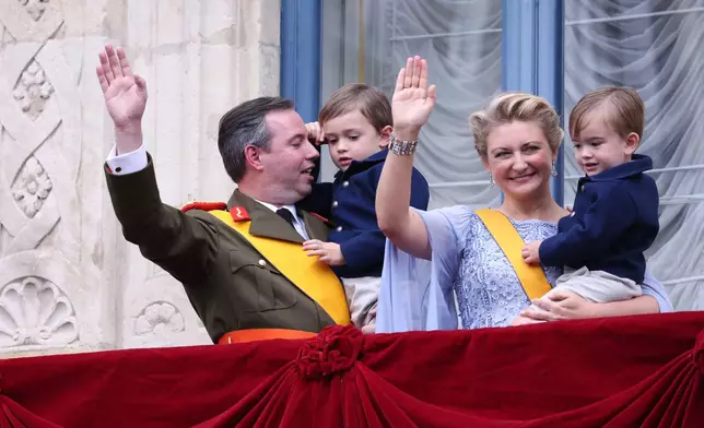 Luxembourg's Grand Duke Guillaume and Luxembourg's Grand Duchess Stephanie hold their children Prince Charles and Prince Francois as they wave from the balcony of the Grand Ducal Palace in Luxembourg, Friday, Oct. 3, 2025. (AP Photo/Omar Havana)