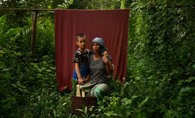 Naung Pate, right, poses for a portrait with her son after foraging for food in the forest near the refugee camp, in the Tak province of Thailand, Saturday, Aug. 30, 2025. (AP Photo/Bram Janssen)