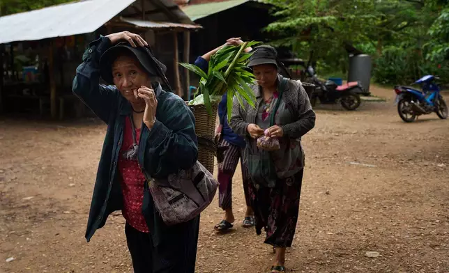 A woman smokes tobacco after returning from foraging for food outside their refugee camp in the Tak province of Thailand, Tuesday, Aug. 26, 2025. (AP Photo/Bram Janssen)