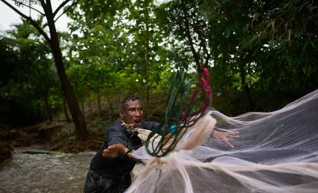 Mahmud Karmar throws a fishing net into the river near the Mae La refugee camp in the Tak province of Thailand, Thursday, Aug. 28, 2025. (AP Photo/Bram Janssen)