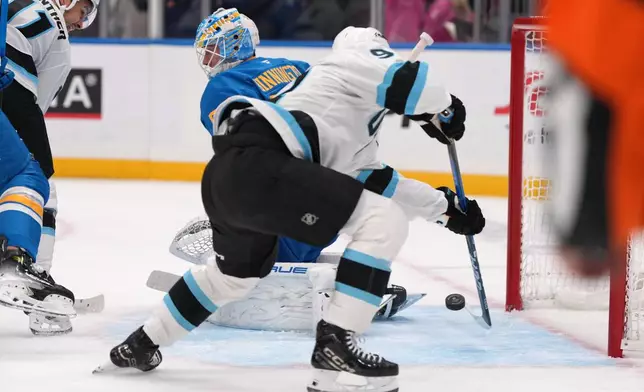 Utah Mammoth's Logan Cooley, right, scores past St. Louis Blues goaltender Jordan Binnington, left, for his third goal of the first period of an NHL hockey game Thursday, Oct. 23, 2025, in St. Louis. (AP Photo/Jeff Roberson)