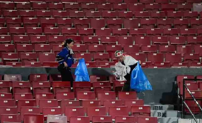 Japan fans clean up trash from the stands after a FIFA U-20 World Cup Group A soccer match against Chile at National Stadium in Santiago, Chile, Tuesday, Sept. 30, 2025. (AP Photo/Matias Delacroix)
