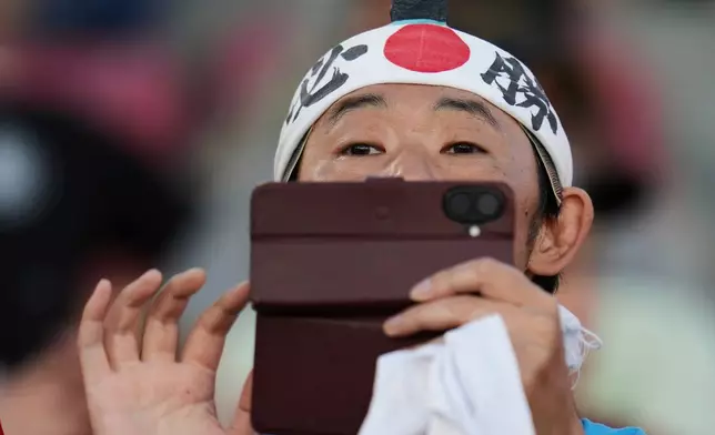 A fan from Japan takes a picture prior to a FIFA U-20 World Cup round of sixteen soccer match between Japan and France at National Stadium in Santiago, Chile, Wednesday, Oct. 8, 2025. (AP Photo/Esteban Felix)