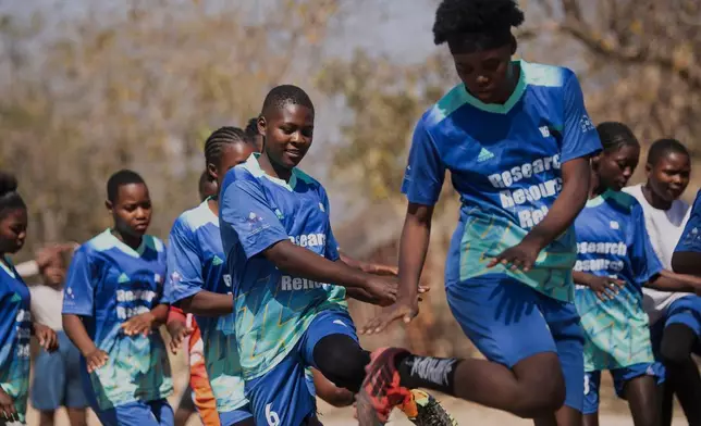Girls warm up for a soccer match as part of activities against early child marriages and teen pregnancies at a school in Shamva, Zimbabwe, Friday, Aug. 29, 2025. (AP Photo/Aaron Ufumeli)