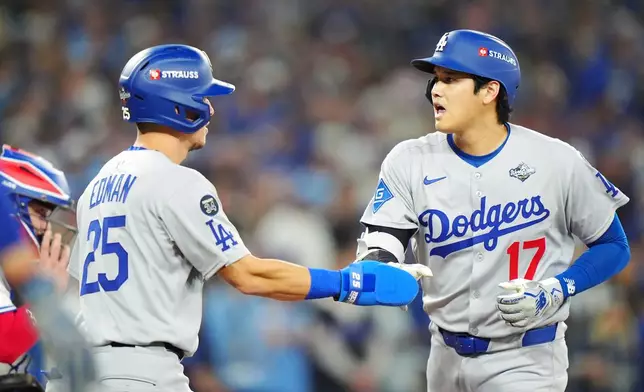Los Angeles Dodgers' Shohei Ohtani (17) celebrates with Tommy Edman (25) after hitting a two-run home run against the Toronto Blue Jays during the seventh inning of Game 1 of baseball's World Series in Toronto, Friday, Oct. 24, 2025. (Frank Gunn/The Canadian Press via AP)