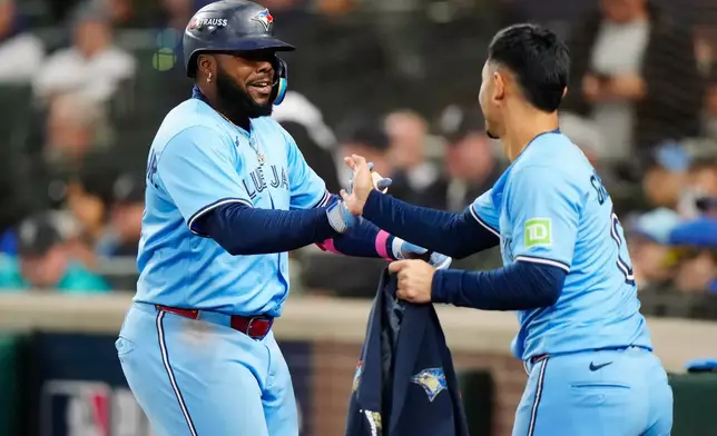 Toronto Blue Jays' Vladimir Guerrero Jr., left, celebrates with Andres Gimenez (0) after hitting a solo home run against the Seattle Mariners during fifth inning Game 3 American League Championship Series baseball action in Seattle on Wednesday, Oct. 15, 2025. (Frank Gunn/The Canadian Press via AP)