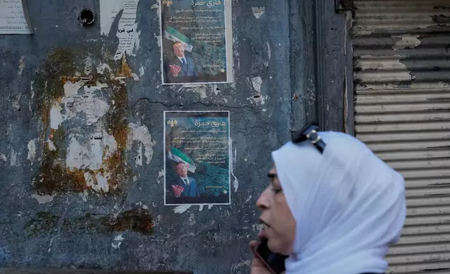 A Syrian woman passes in front of posters showing Syrian-American Jew Henry Hamra, a candidate for the Syrian Parliamentary elections, in the Jewish neighborhood of old Damascus, Syria Friday, Oct. 3, 2025. (AP Photo/Hussein Malla)