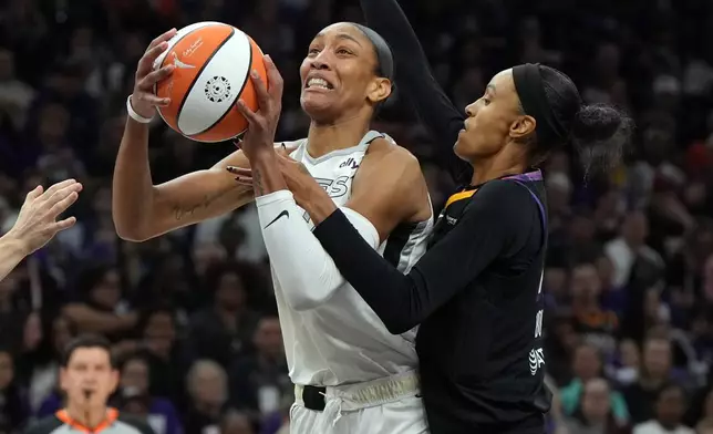 Phoenix Mercury forward DeWanna Bonner, right, fouls Las Vegas Aces center A'ja Wilson, left, during the first half of Game 4 of the WNBA basketball finals, Friday, Oct. 10, 2025, in Phoenix. (AP Photo/Rick Scuteri)