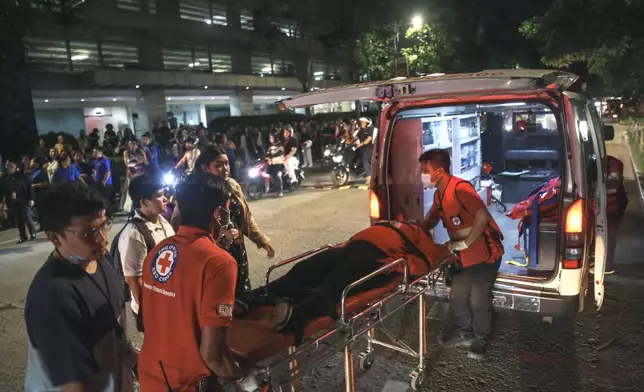 Medical workers load a resident into an ambulance as others stay outside buildings after a strong earthquake struck Cebu city, central Philippines, on Tuesday, Sept. 30, 2025. (AP Photo/Jacqueline Hernandez)