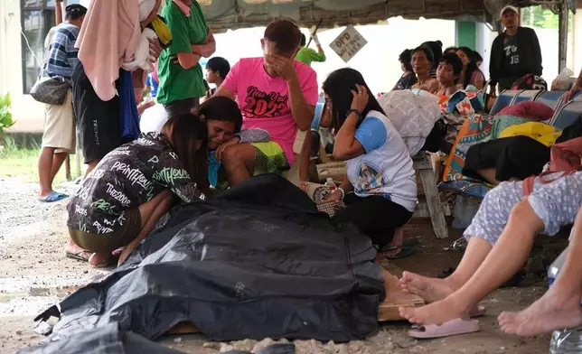 People surround a body bag in Bogo City, Cebu province, Philippines Wednesday, Oct. 1, 2025 after an offshore earthquake on late Tuesday. (AP Photo)