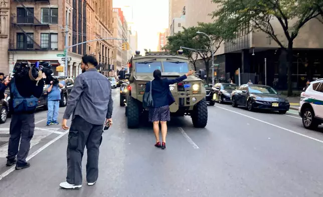 A woman stands in front of an armored vehicle operated by federal agents on Lafayette Street as demonstrators follow along after an immigration sweep on Canal Street through Chinatown, Tuesday, Oct. 21, 2025, in New York. (AP Photo/Jake Offenhartz)