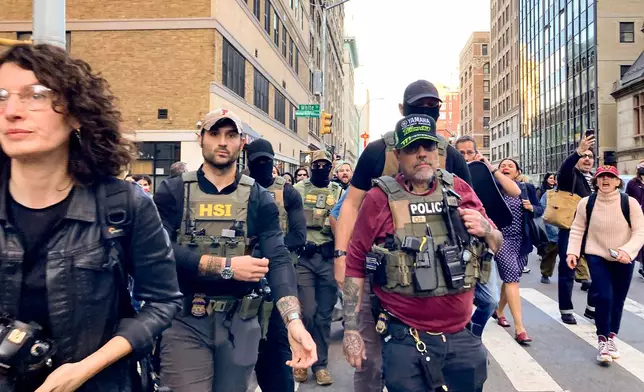 Federal agents walk down Lafayette Street as demonstrators follow behind after an immigration sweep on Canal Street through Chinatown, Tuesday, Oct. 21, 2025, in New York. (AP Photo/Jake Offenhartz)