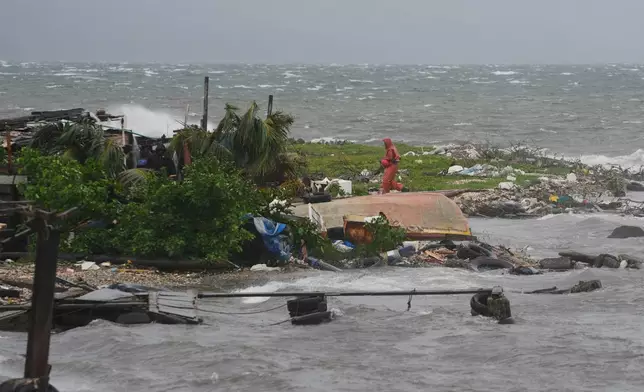 A man walks along the coastline in Kingston, Jamaica, as Hurricane Melissa approaches, Tuesday, Oct. 28, 2025. (AP Photo/Matias Delacroix)