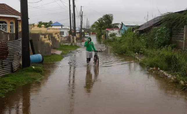 A man wades through a flooded street ahead of the forecasted arrival of Hurricane Melissa in Old Harbour, Jamaica, Monday, Oct. 27, 2025. (AP Photo/Matias Delacroix)