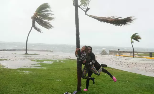 A couple jokes around on the coast in Kingston, Jamaica, as Hurricane Melissa approaches, Tuesday, Oct. 28, 2025. (AP Photo/Matias Delacroix)