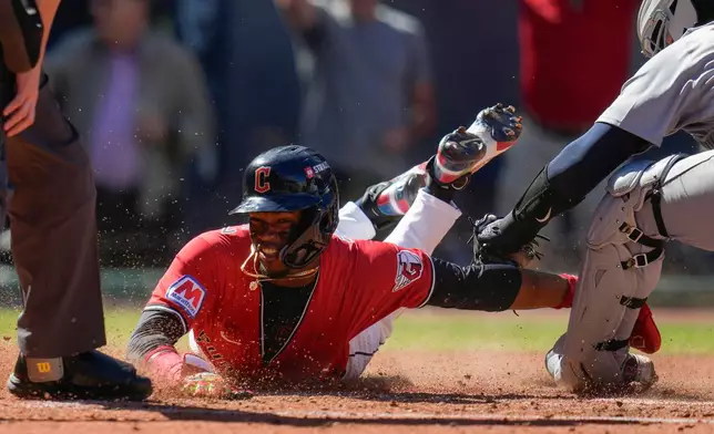 Cleveland Guardians' Angel Martínez scores on a single hit by Gabriel Arias as Detroit Tigers catcher Dillon Dingler, right, reaches with the tag during the fourth inning of Game 1 of the American League Wild Card baseball playoff series in Cleveland, Tuesday, Sept. 30, 2025. (AP Photo/Sue Ogrocki)