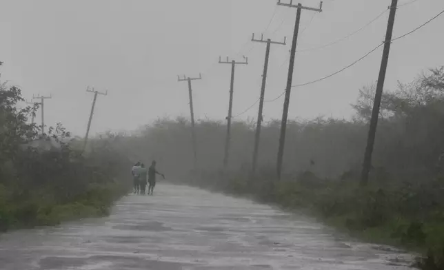 People walk along a road during the passing of Hurricane Melissa in Rocky Point, Jamaica, Tuesday, Oct. 28, 2025. (AP Photo/Matias Delacroix)