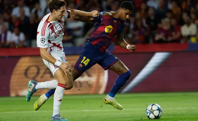Olympiacos' Panagiotis Retsos, left, holds Barcelona's Marcus Rashford during the Champions League opening phase soccer match between Barcelona and Olympiacos in Barcelona, Spain, Tuesday, Oct. 21, 2025. (AP Photo/Joan Monfort)