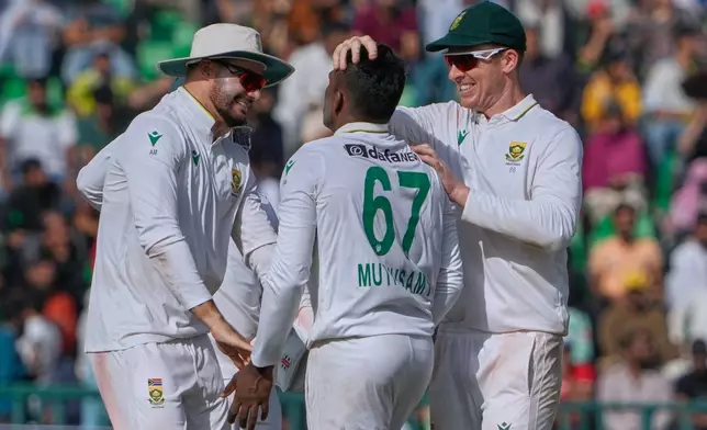 South Africa's Senuran Muthusamy, center, is congratulated by teammates after he taking the wicket of Pakistan's Saud Shakeel during the first day of of first test cricket match between Pakistan and South Africa, in Lahore, Pakistan, Sunday, Oct. 12, 2025. (AP Photo/K.M. Chaudary)