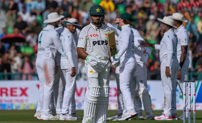 Pakistan's Babar Azam, front, walks off the field as South African players celebrate after his dismissal during the first day of first test cricket match between Pakistan and South Africa, in Lahore, Pakistan, Sunday, Oct. 12, 2025. (AP Photo/K.M. Chaudary)