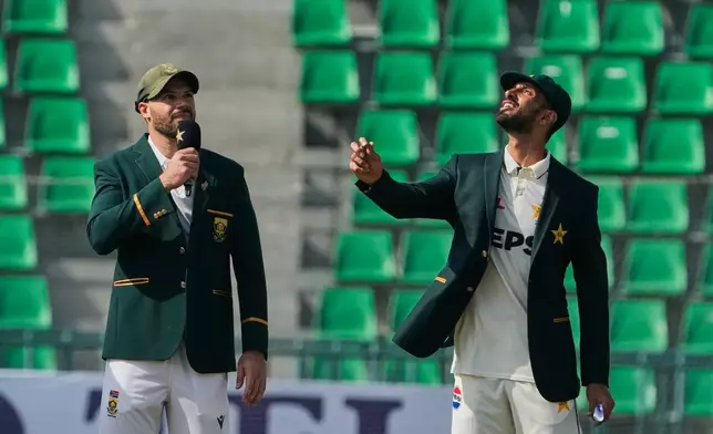 Pakistan's Shan Masood, right, flips the coin for toss as South Africa's Aiden Markram watches before the start of the play of the first test cricket match between Pakistan and South Africa, in Lahore, Pakistan, Sunday, Oct. 12, 2025. (AP Photo/K.M. Chaudary)