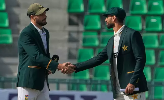 Pakistan's Shan Masood, right, shakes hand with South Africa's Aiden Markram after the toss before the start of the play of the first test cricket match between Pakistan and South Africa, in Lahore, Pakistan, Sunday, Oct. 12, 2025. (AP Photo/K.M. Chaudary)