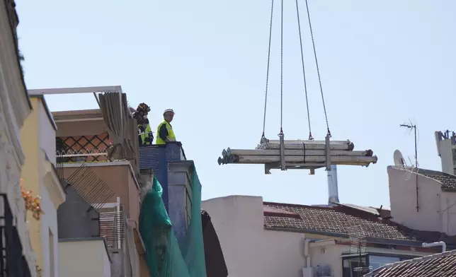 Rescue workers stand on the roof at the scene of a building collapse in Madrid, Spain, on Tuesday, Oct. 7, 2025. (AP Photo/Manu Fernandez)