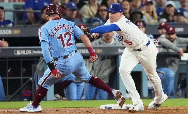 Philadelphia Phillies' Kyle Schwarber, left, is tagged out by Los Angeles Dodgers first baseman Freddie Freeman on a pickoff throw from catcher Will Smith during the seventh inning in Game 3 of baseball's National League Division Series Wednesday, Oct. 8, 2025, in Los Angeles. (AP Photo/Jae C. Hong)