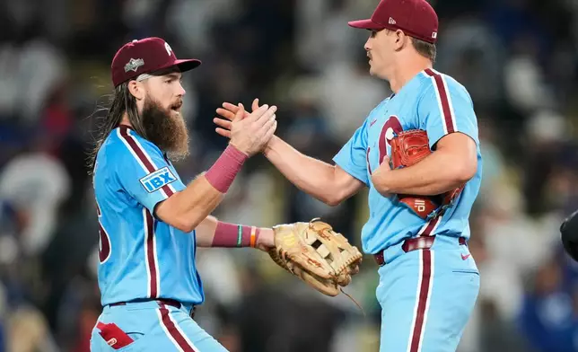Philadelphia Phillies pitcher Tanner Banks shakes hands with center fielder Brandon Marsh after a win over the Los Angeles Dodgers in Game 3 of baseball's National League Division Series Wednesday, Oct. 8, 2025, in Los Angeles. (AP Photo/Mark J. Terrill)