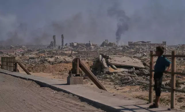 A displaced Palestinian boy looks at smoke rising into the sky following an Israeli military strike in Gaza City, as seen from the central Gaza Strip, Thursday, Oct. 2, 2025. (AP Photo/Abdel Kareem Hana)