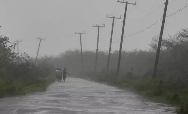 People walk along a road during the passing of Hurricane Melissa in Rocky Point, Jamaica, Tuesday, Oct. 28, 2025. (AP Photo/Matias Delacroix)