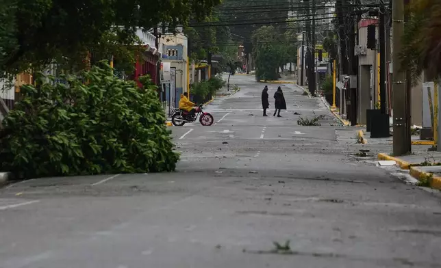 People walk in Kingston, Jamaica, as Hurricane Melissa approaches, Tuesday, Oct. 28, 2025. (AP Photo/Matias Delacroix)